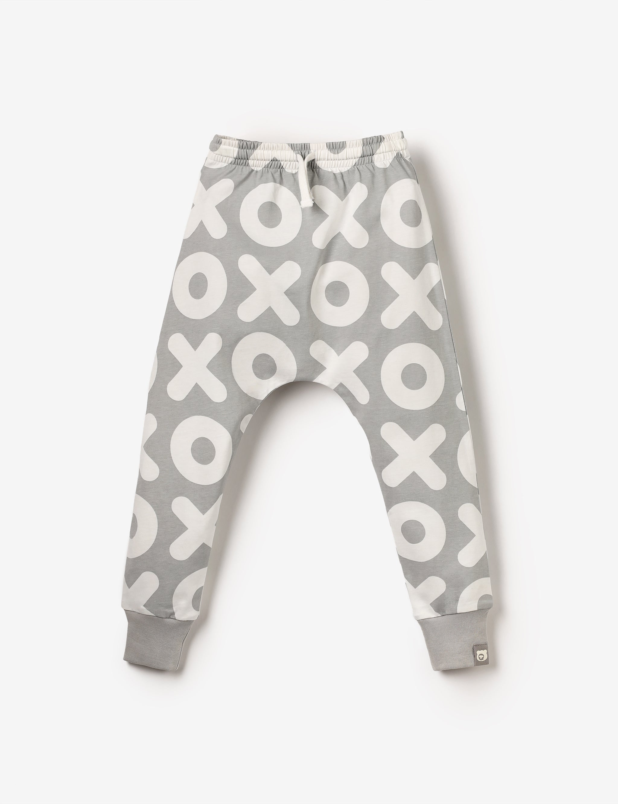 Flat lay of white and grey kids joggers with XOXO all-over-print, made from soft GOTS-certified organic cotton jersey – unisex, sensory-friendly, comfy and perfect for any adventure.