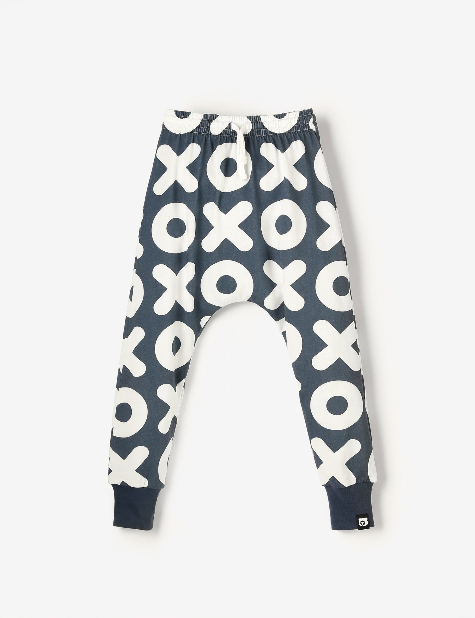 Flat lay of white and navy blue kids joggers with XOXO all-over-print, made from soft GOTS-certified organic cotton jersey – unisex, sensory-friendly, comfy and perfect for any adventure.